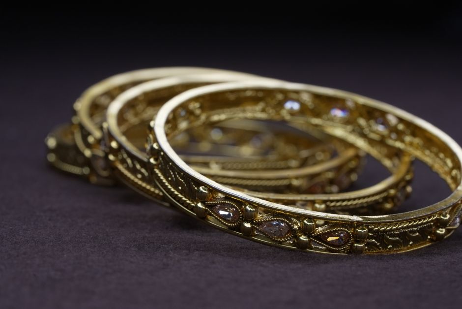Bangles de oro con detalle fino sobre fondo oscuro